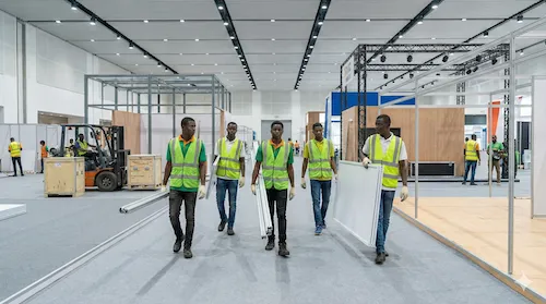 Équipe modulaire.africa transportant des panneaux modulaires dans un hall d'exposition